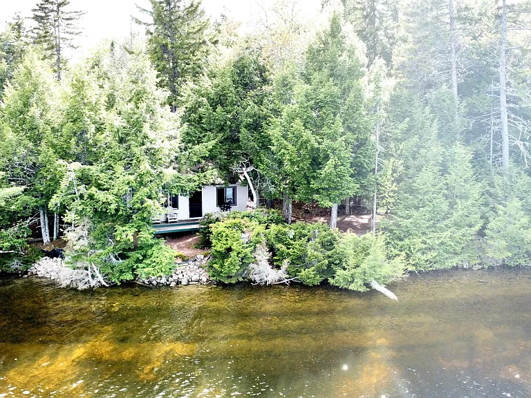 Escape to the wild beauty of Maine with this unique off-grid two-bedroom cabin nestled on leased land along the pristine shores of Pemadumcook Lake. $149,900